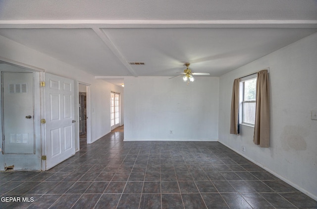 empty room featuring dark tile patterned floors, visible vents, baseboards, and ceiling fan