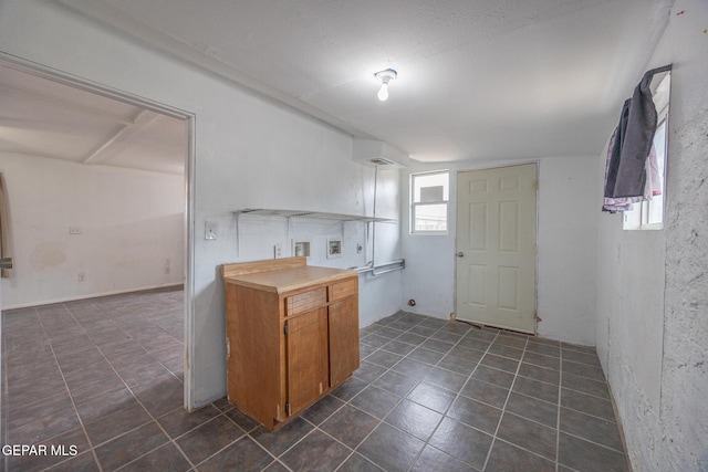 kitchen with brown cabinets, dark tile patterned flooring, and light countertops