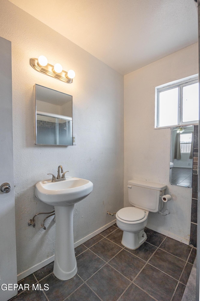 bathroom featuring baseboards, toilet, and tile patterned flooring