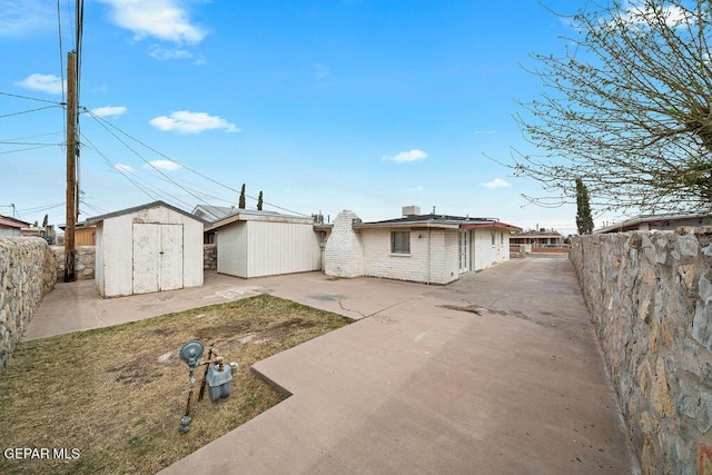 rear view of property with a patio area, an outbuilding, a storage shed, and fence