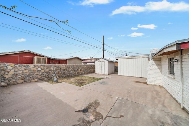 view of yard with an outbuilding, a storage unit, a patio area, and fence