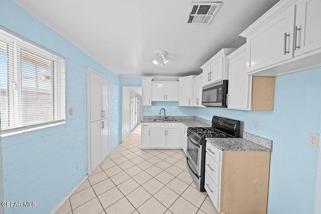 kitchen featuring light tile patterned floors, light stone counters, visible vents, a sink, and appliances with stainless steel finishes