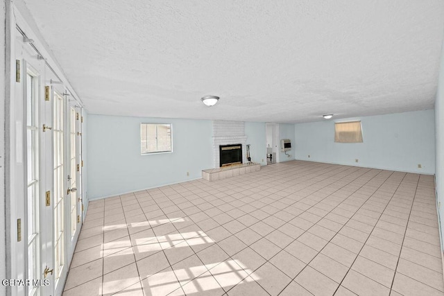 unfurnished living room with a textured ceiling, a brick fireplace, and light tile patterned flooring