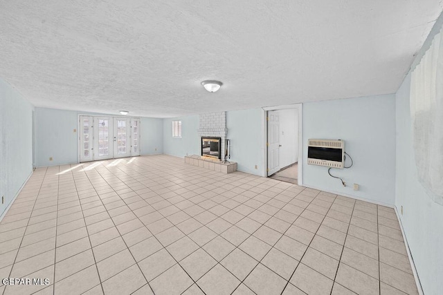 unfurnished living room with heating unit, a fireplace, a textured ceiling, and light tile patterned flooring