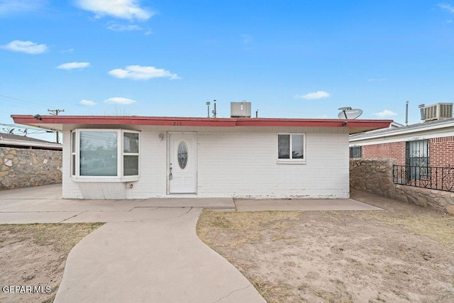 ranch-style home featuring concrete block siding, cooling unit, fence, and a patio