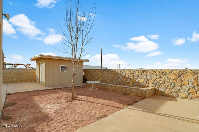 exterior space featuring a fenced backyard, an outdoor structure, a shed, and a patio area