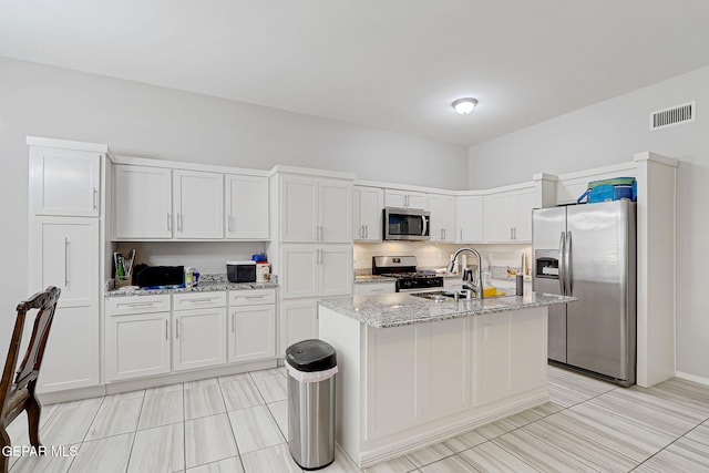 kitchen featuring light stone counters, visible vents, a sink, appliances with stainless steel finishes, and white cabinetry