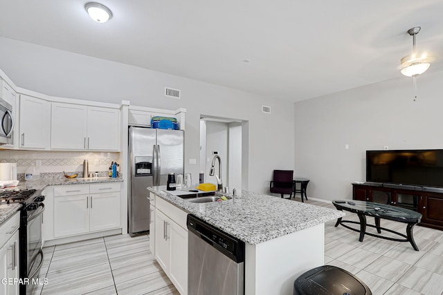 kitchen featuring visible vents, a sink, appliances with stainless steel finishes, white cabinetry, and backsplash