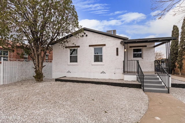 back of house with brick siding and fence