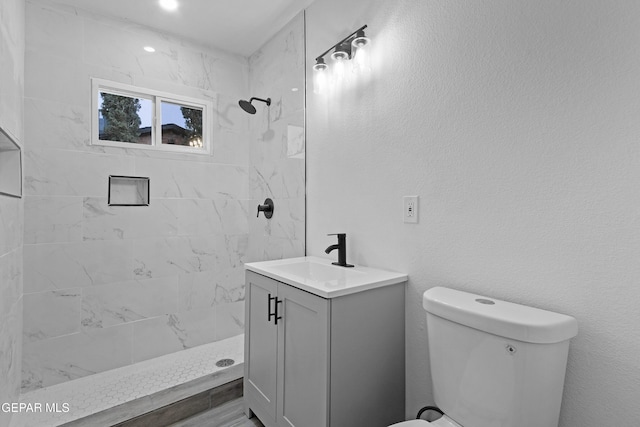 full bathroom with vanity, toilet, a shower stall, and a textured wall