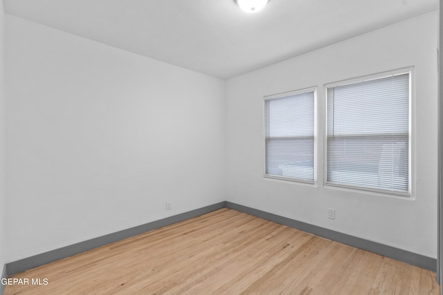 spare room featuring baseboards and light wood-style floors