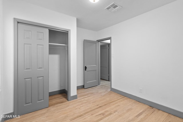 unfurnished bedroom with a closet, visible vents, light wood-style flooring, and baseboards