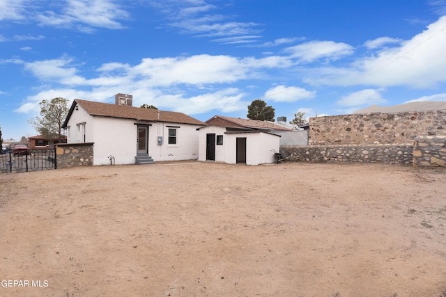 back of property with entry steps, fence, and stucco siding