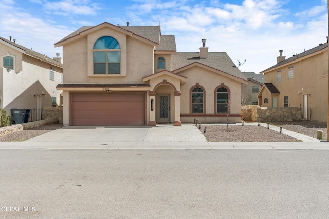 traditional-style house featuring a shingled roof, concrete driveway, stucco siding, a chimney, and an attached garage