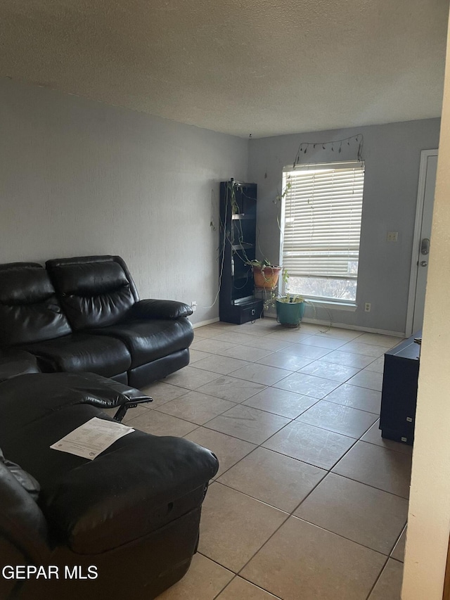 living area featuring tile patterned floors, baseboards, and a textured ceiling