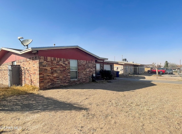 back of house with brick siding, an attached garage, and fence