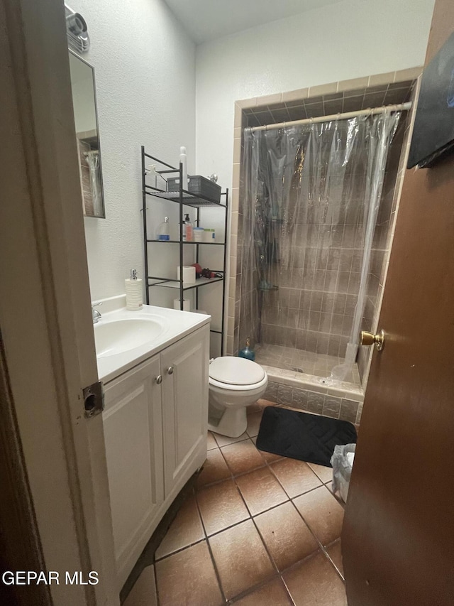 bathroom with tile patterned flooring, a stall shower, toilet, and vanity