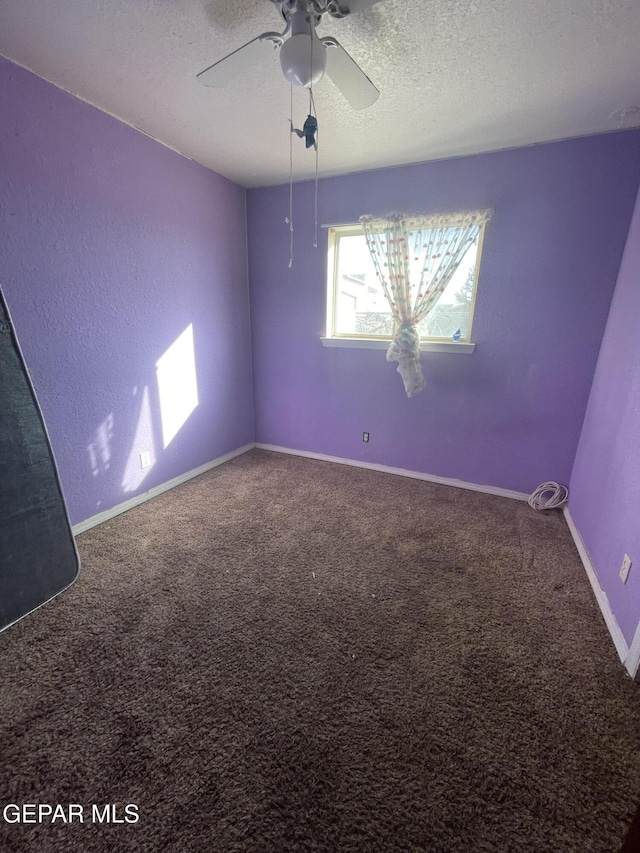 empty room with baseboards, a textured ceiling, carpet, and a ceiling fan