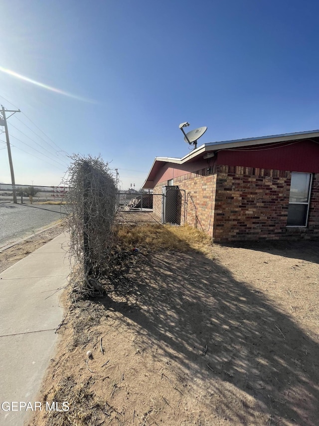 view of side of property with fence and brick siding