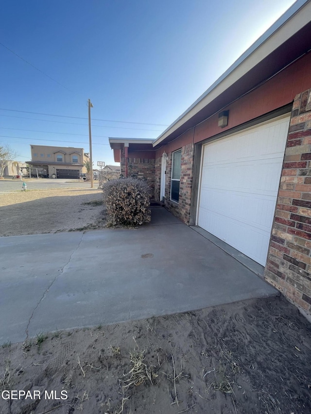 view of property exterior featuring concrete driveway and brick siding