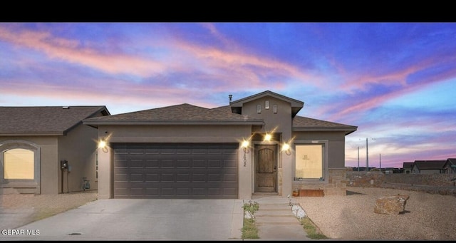 single story home featuring a shingled roof, concrete driveway, an attached garage, and stucco siding