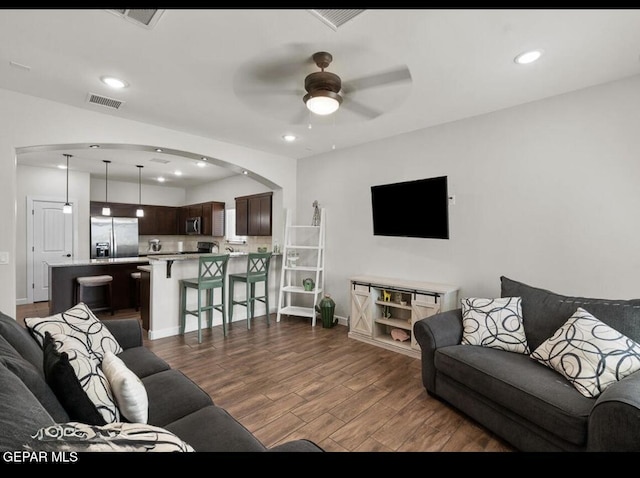 living room featuring visible vents, ceiling fan, recessed lighting, arched walkways, and dark wood-style flooring