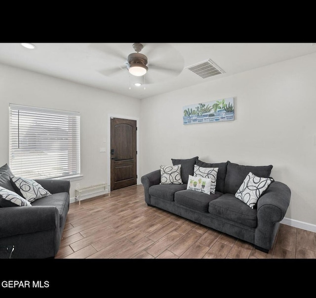 living room with a ceiling fan, wood finished floors, visible vents, and baseboards