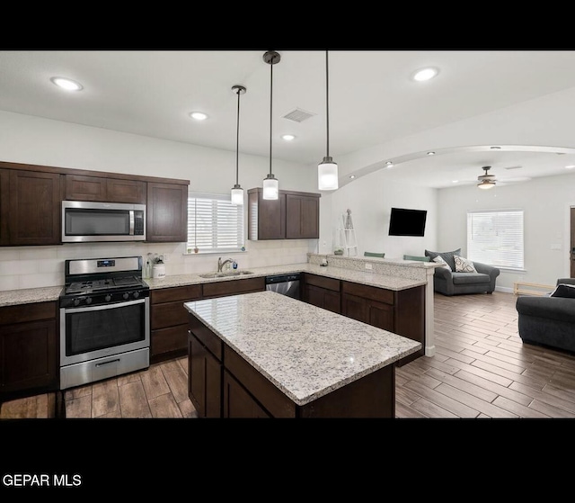 kitchen with wood finish floors, visible vents, a ceiling fan, open floor plan, and appliances with stainless steel finishes