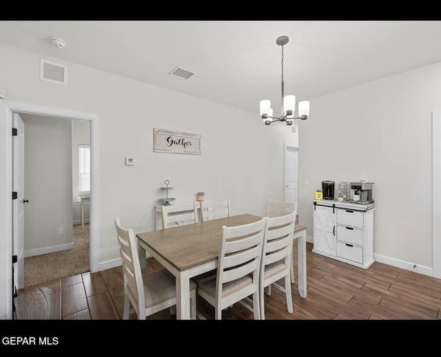 dining room featuring wood finish floors, visible vents, and an inviting chandelier