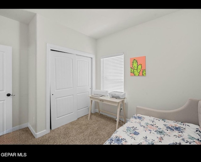 carpeted bedroom with a closet and baseboards