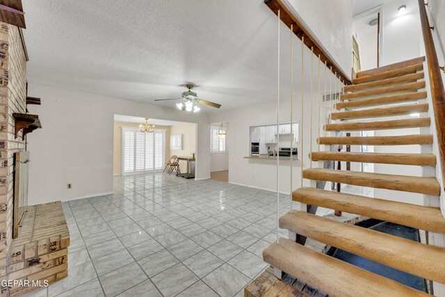 living room featuring visible vents, ceiling fan with notable chandelier, a textured ceiling, baseboards, and stairs