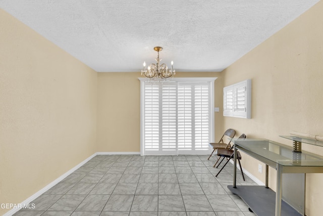 unfurnished dining area featuring a textured ceiling, baseboards, and a chandelier