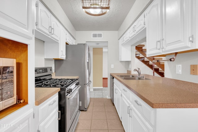 kitchen featuring visible vents, light tile patterned floors, stainless steel appliances, a textured ceiling, and a sink