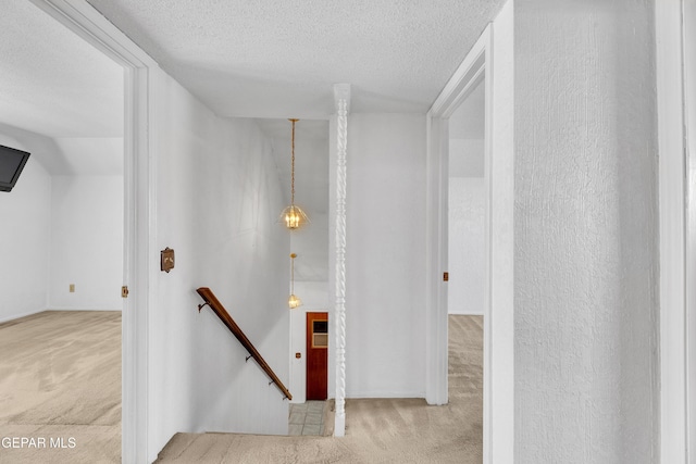 staircase with carpet flooring and a textured ceiling