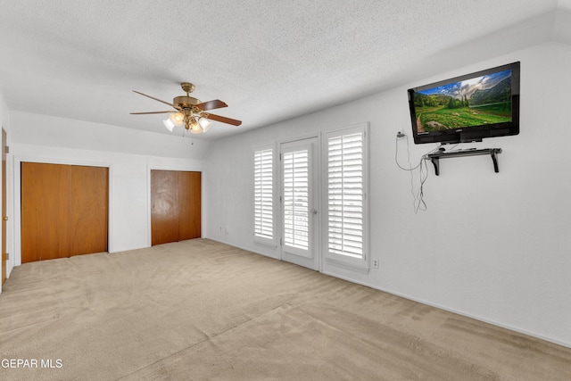 unfurnished bedroom featuring two closets, a textured ceiling, carpet, and access to outside