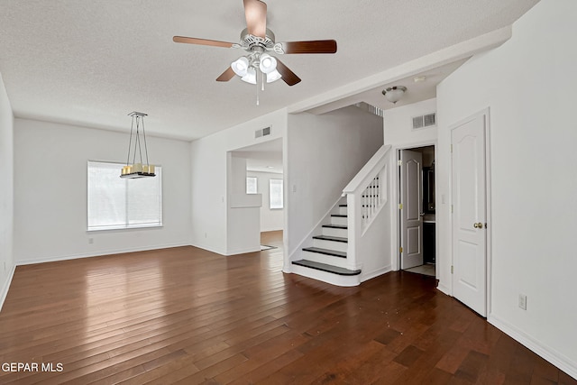 unfurnished living room with visible vents, a ceiling fan, a textured ceiling, dark wood finished floors, and stairs