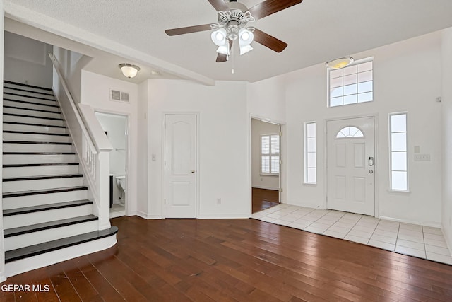 foyer featuring visible vents, baseboards, ceiling fan, stairs, and hardwood / wood-style flooring