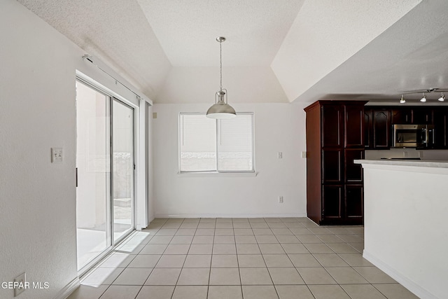 interior space with light tile patterned floors, a healthy amount of sunlight, and vaulted ceiling