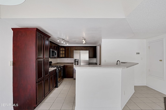 kitchen with a textured ceiling, stainless steel appliances, reddish brown cabinets, light tile patterned flooring, and light countertops