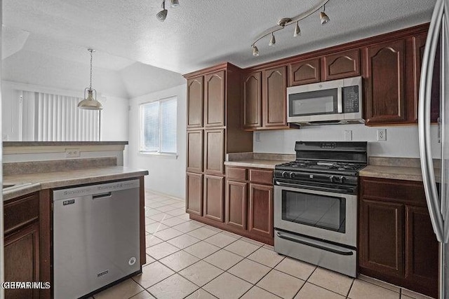 kitchen featuring light tile patterned floors, vaulted ceiling, pendant lighting, appliances with stainless steel finishes, and a textured ceiling