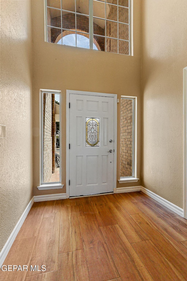 foyer entrance featuring a high ceiling, a textured wall, and wood-type flooring