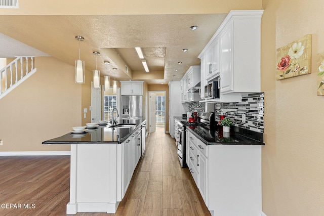 kitchen featuring decorative backsplash, dark countertops, light wood-style floors, and appliances with stainless steel finishes