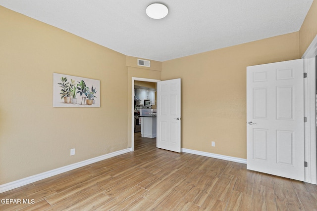 unfurnished bedroom with visible vents, baseboards, and light wood-style floors