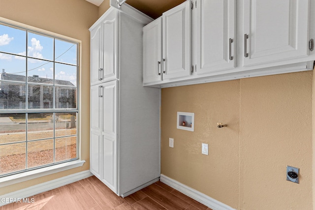 laundry area featuring baseboards, hookup for an electric dryer, cabinet space, washer hookup, and light wood-style floors