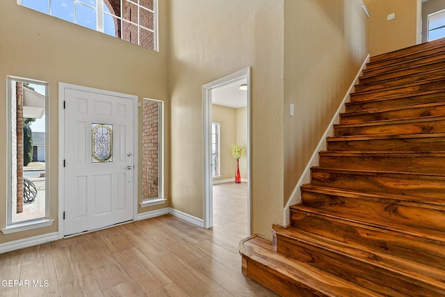 foyer entrance with stairway, wood finished floors, baseboards, and a wealth of natural light