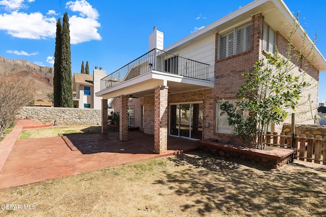 back of property featuring a patio, a balcony, brick siding, and fence