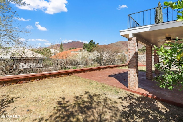 view of yard featuring a mountain view, a ceiling fan, a fenced backyard, and a patio