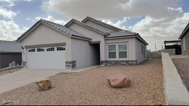 view of front of property featuring concrete driveway, a tiled roof, a garage, and stucco siding