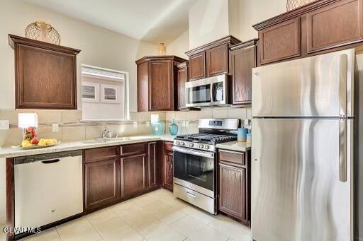 kitchen featuring decorative backsplash, appliances with stainless steel finishes, light countertops, and a sink