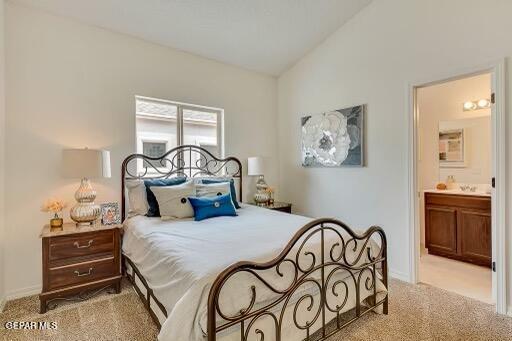 bedroom featuring ensuite bathroom, carpet flooring, and vaulted ceiling